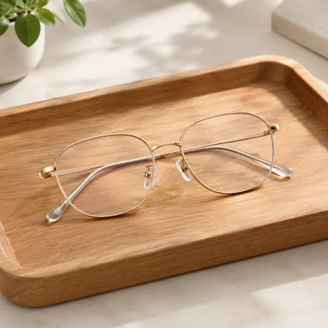 Gold-rim eyeglasses on a wooden tray.