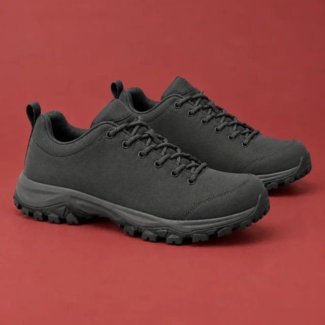 Pair of plain charcoal hiking shoes on a muted red studio surface.