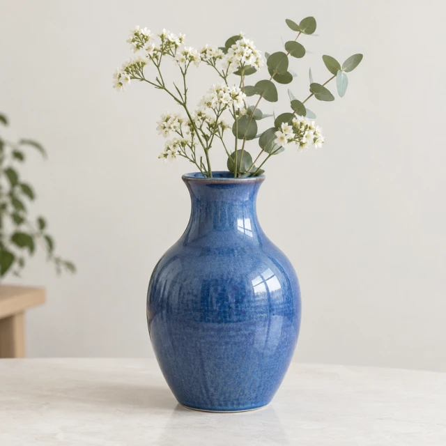 Blue ceramic vase isolated on a plain light background.