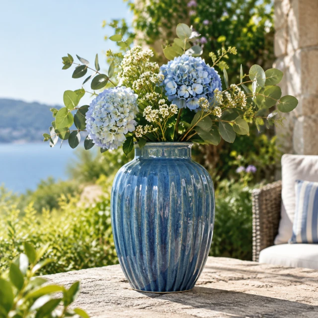 Blue ceramic vase outdoors on a stone surface.