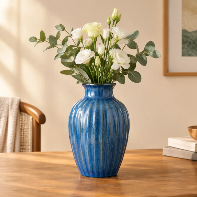 Blue ceramic vase against a clean warm studio background, framed as a square product image.