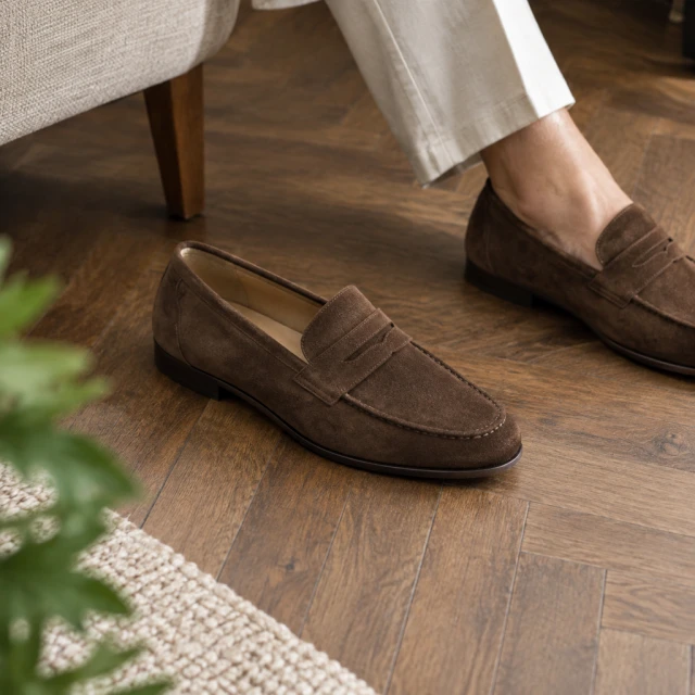Suede loafers on a herringbone wood floor.