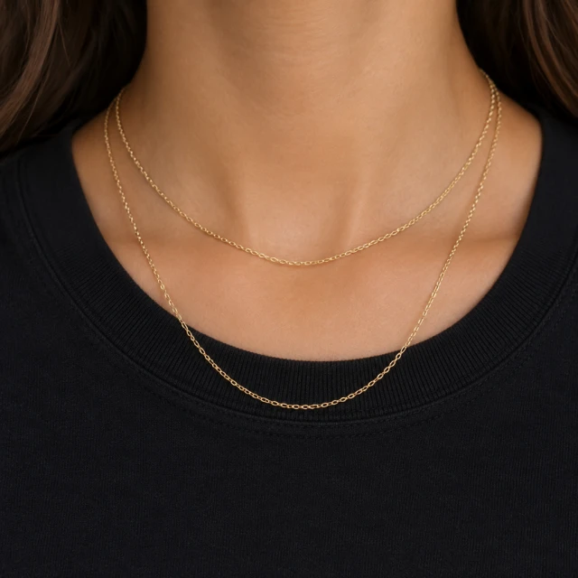 Layered gold necklaces against a dark top