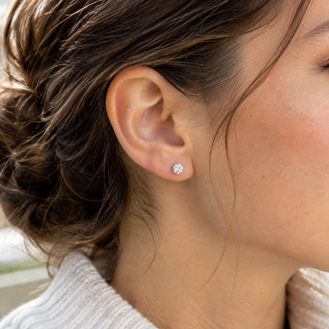 Small stud earrings worn by an adult, shown in a close detail crop.