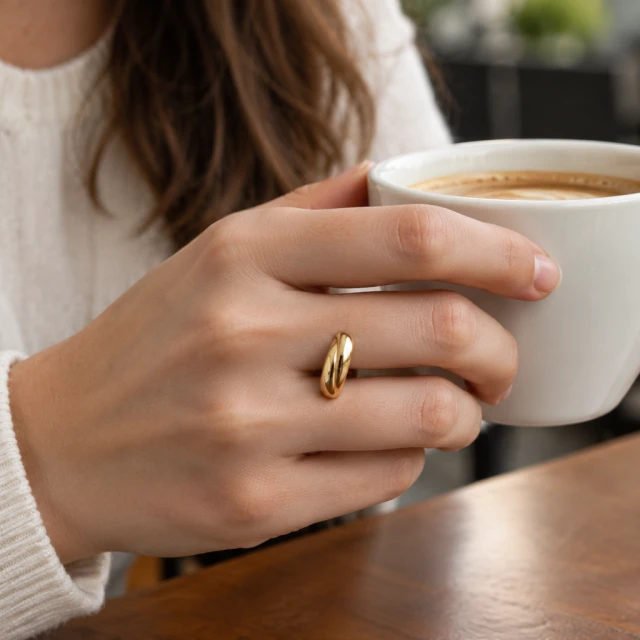 Gold ring on a hand holding a coffee cup.