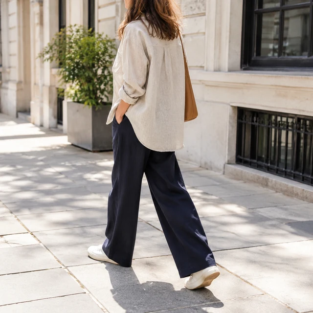 Adult wearing a linen overshirt and navy trousers on a city walk.