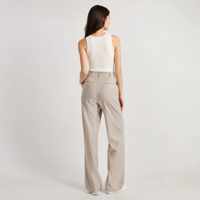 Model wearing tailored trousers, full length, neutral studio.