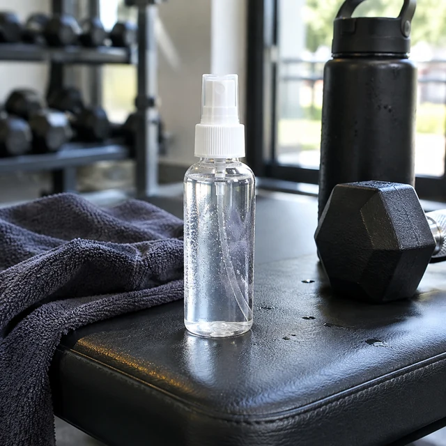 Face mist bottle on a gym bench after a workout, phone-camera look.