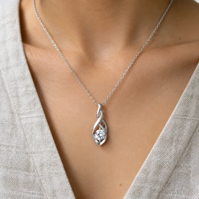 Silver pendant necklace worn on a linen neckline.