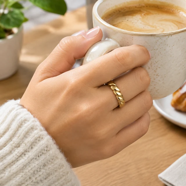 Gold ring on a hand holding a coffee cup.