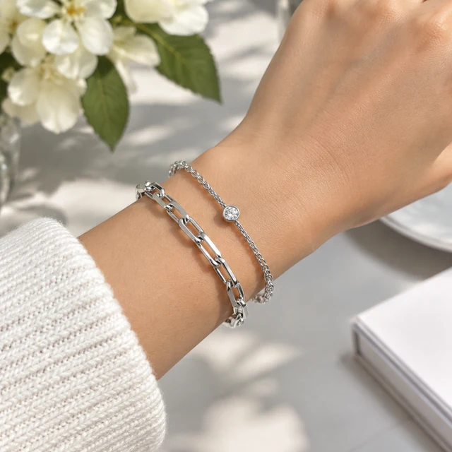 Silver bracelet stacked on a wrist in daylight.