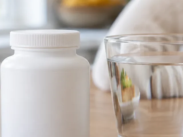 Tight crop of Vitamin bottle beside a glass of water at breakfast. with one edge cut off